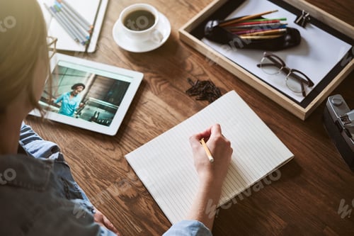 Preview: Woman sketching designs in a notepad while working from home
