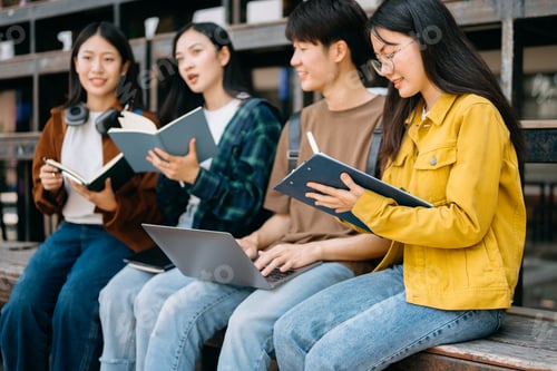 Preview: Young people college students is reading a book while relaxing sitting on grass in a campus park