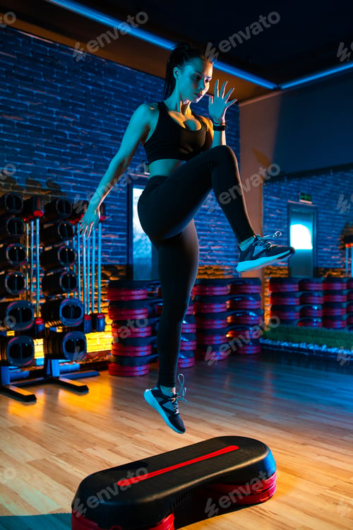Preview: Woman in black sportswear using step platform at gym. Aerobic and fitness exercises.