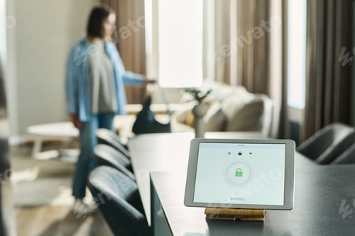 Preview: Caucasian Young Woman Standing in Living Room While Using Home Security Tablet