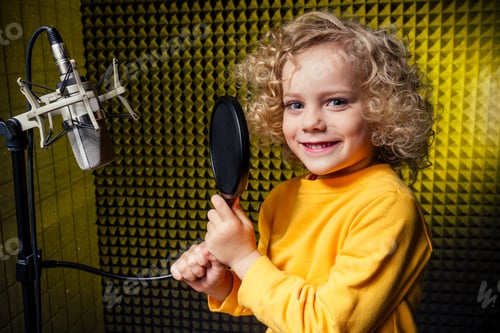 Preview: girl blonde curly hair style star singer artist in a yellow blouse with headphone recording