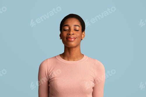 Preview: Portrait Of Pleased Black Woman Standing With Closed Eyes On Blue Background