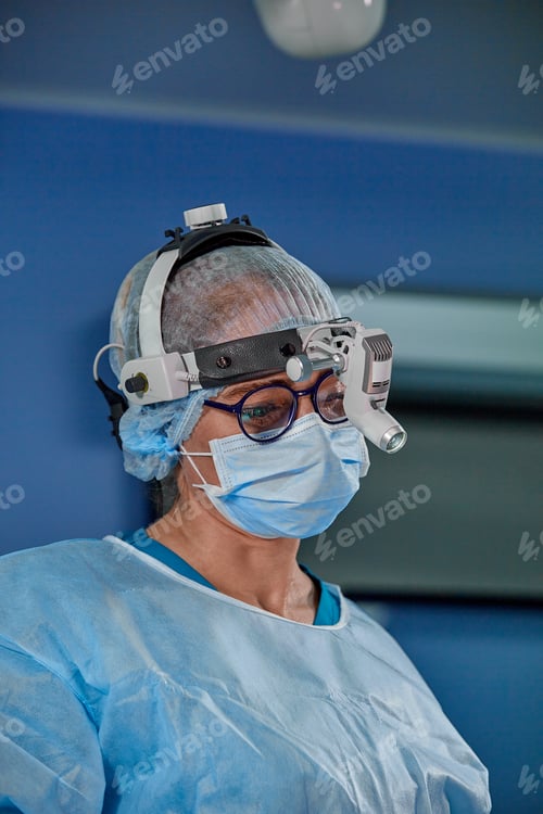 Preview: Close up portrait of female surgeon doctor wearing protective mask and hat during the operation