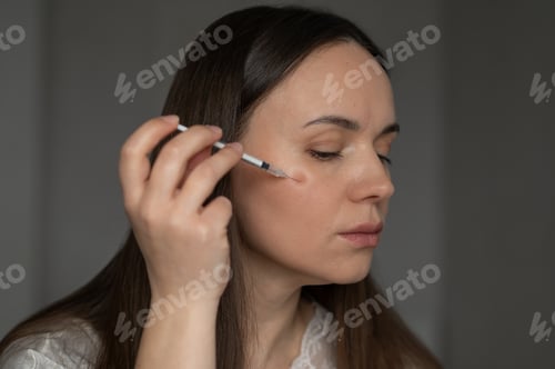 Preview: Young woman giving beauty injection to her face