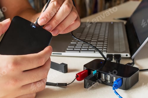 Preview: Male hand connecting the hard drive with a USB cable to a laptop computer