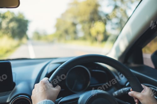 Preview: Closeup image of a woman holding steering wheel while driving a car on the road