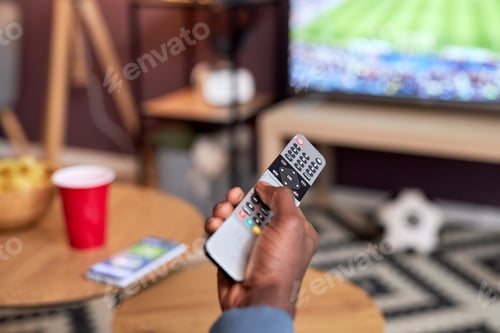 Preview: Close up of black young man watching football match at home