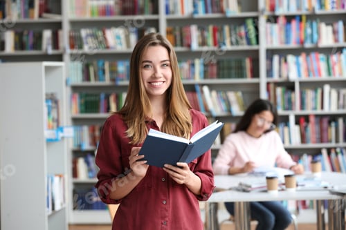 Preview: Young pretty woman with book in library