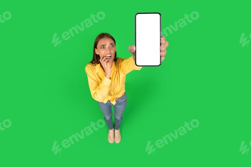 Preview: Shocked Female Showing Cellphone With Empty Screen On Green Background