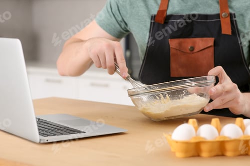 Preview: Man learning to cook with online video at wooden table indoors, closeup. Time for hobby
