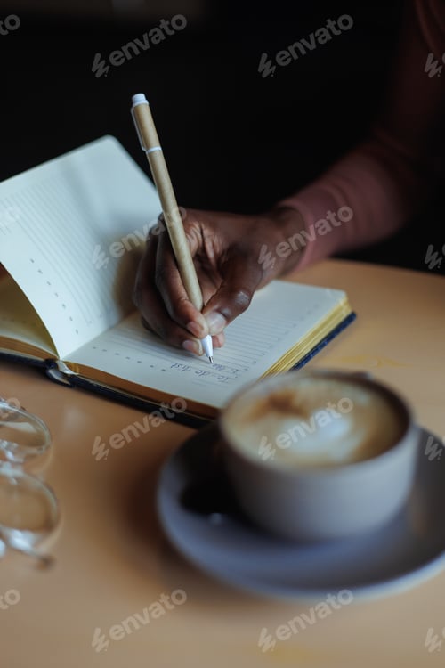 Preview: Cropped photo of African-American woman sitting at table with cup of coffee, glasses in cafe, taking