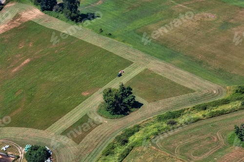 Preview: Aerial View of a tractor cutting the green grass field in a farm