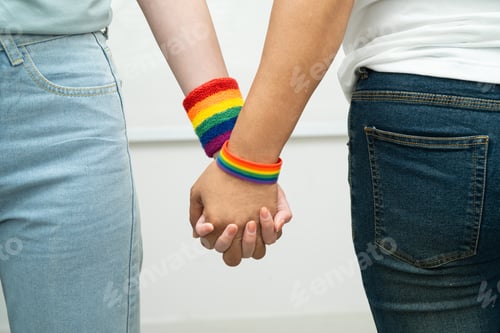 Preview: Asian LGBT couple woman holding hand wearing rainbow wristband.
