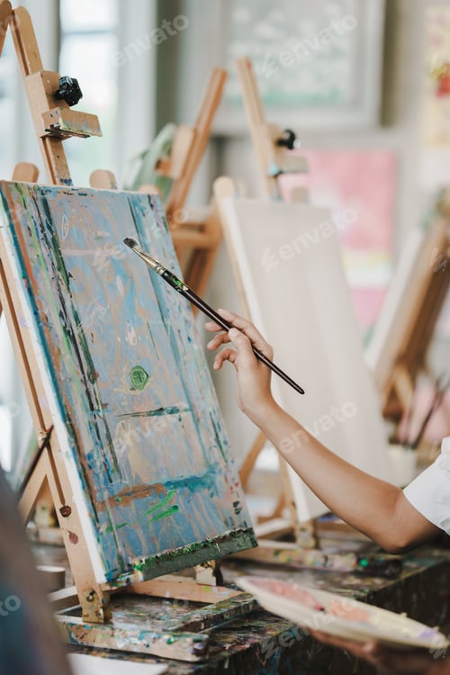 Preview: Close-up of female artist painting on canvas with brush Young painter working on the floor of her ar