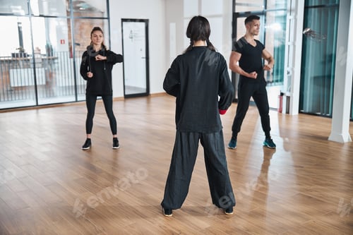Preview: Woman coach watching over two martial arts learners