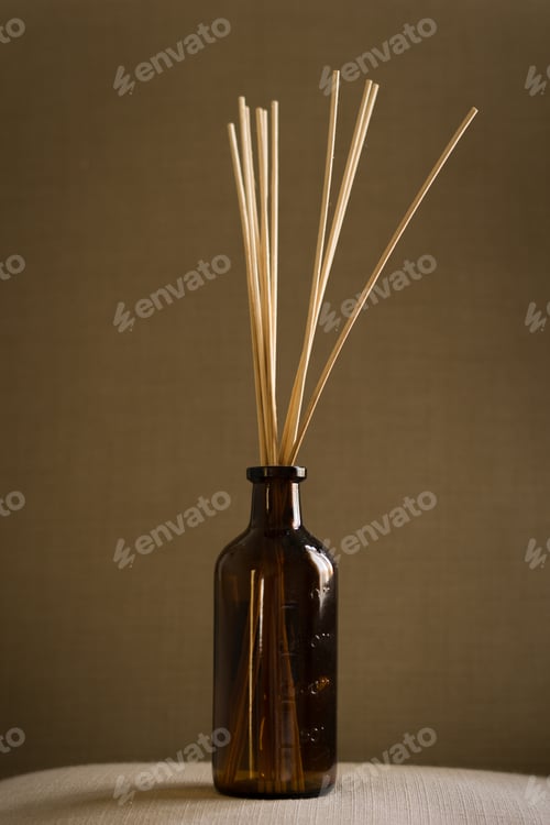 Preview: Dark glass diffuser bottle with natural reed sticks put on a pillow