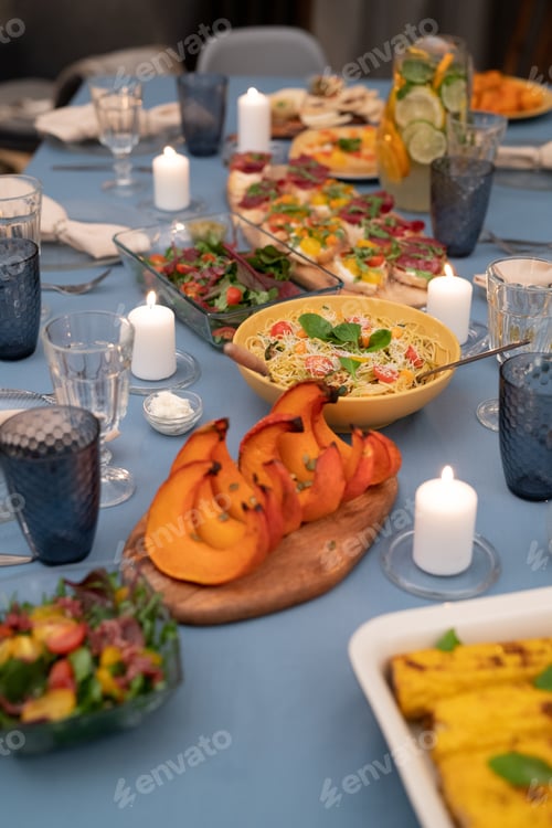 Vista previa: Festive table served with wineglasses, burning candles and vegetarian food