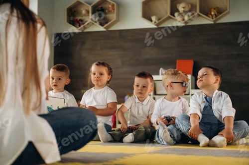 Preview: Teaching, sitting on the floor. Children in kindergarten with their teacher