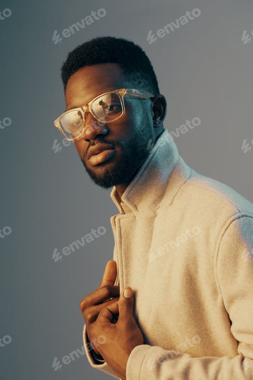 Preview: Stylish young man in glasses wearing a light coat, showcasing confidence against a gradient