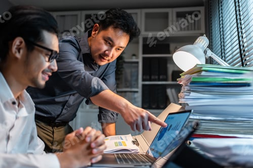 Preview: Asian handsome two businessman using laptop computer working in office.
