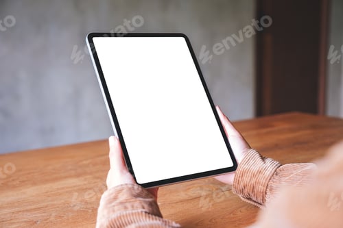 Preview: Person Holding a Tablet at Wooden Table Indoors