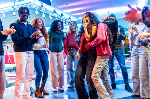 Preview: Happy multi ethnic friends dancing and having fun in a bowling alley