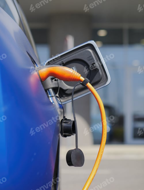 Preview: Vertical closeup shot of an electric car being charged with an orange charger
