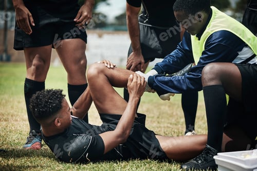 Preview: Cropped shot of a young rugby player receiving first aid assistance on the field