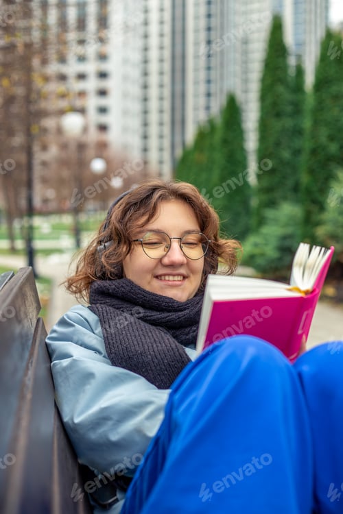 Preview: Girl reading a book in the city. Girl reading a book and listening to music.