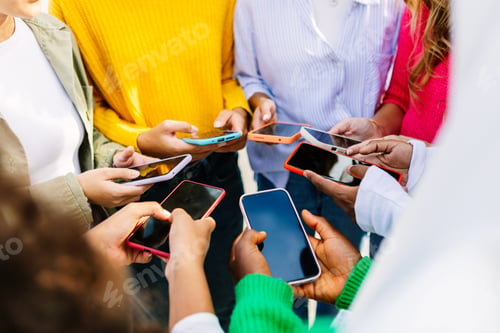 Preview: Young group of people using mobile phones together at city street.