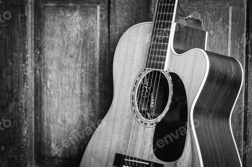 Preview: Beautiful grayscale shot of an acoustic guitar leaned on a wooden door on a wooden surface