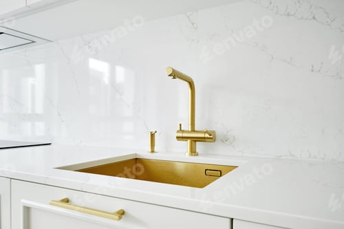 Preview: Stylish modern kitchen sink with gold faucet and white marble countertop during morning light