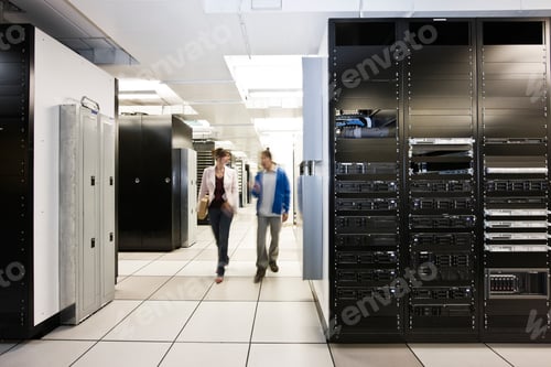 Preview: Computer server room racks with technician in background.