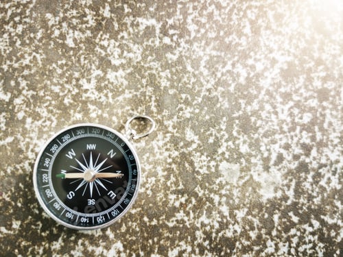 Preview: Compass placed on a small rock, sunset background, text space.