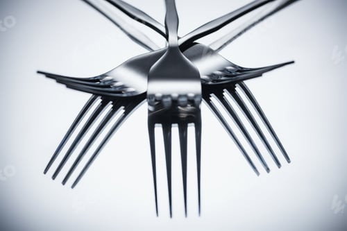 Preview: close-up view of shiny stainless steel forks reflected on grey