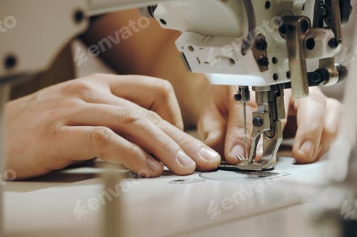 Preview: Tailor man sewing at workplace. Man hands sewing on machine, close-up