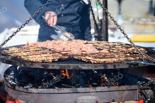 Preview: Cooking chicken barbecue on BBQ grill basket with wooden handle, street food and fast food festival