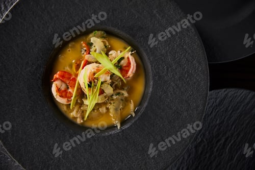 Preview: top view of delicious restaurant soup with shrimps in black plate