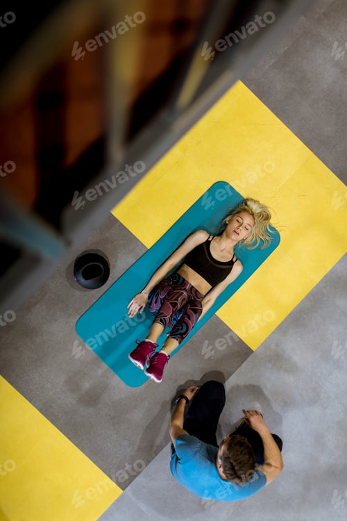 Preview: Top view at sporty woman exercises with assistance of her personal trainer