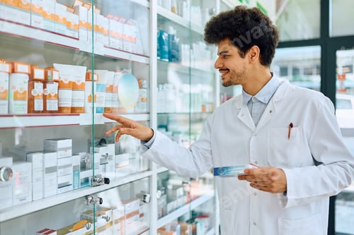 Preview: Happy male pharmacist working in a drugstore.