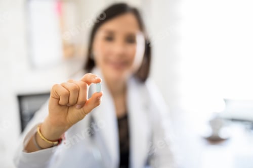 Preview: Female physician holding a pill