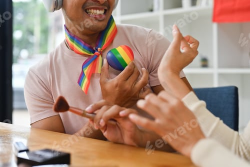 Preview: Smiling gay male beauty blogger or influencer filming review of new cosmetics.