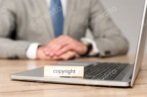 Preview: selective focus of wooden block with word copyright on laptop near businessman sitting at desk