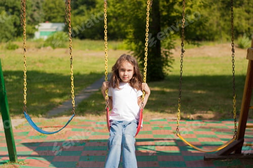 Preview: summer portrait of a little girl swinging on a swing.