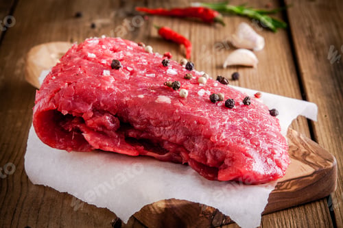 Preview: raw meat steak on a cutting board with garlic and pepper