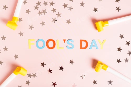 Preview: April Fools' Day written in colored letters, whistles, stars and tulips on pink top view