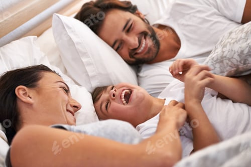 Preview: He always wants to be close to mommy and daddy. Cropped shot of a young family in bed together.