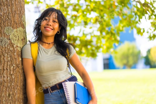 Preview: Asian girl on campus, smiling at university under tree with block in hand and backpack