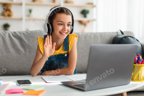 Preview: Girl in headphones using laptop, waving to webcam
