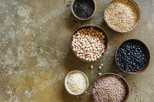 Preview: Different types of beans and rice in coconut bowls, on a brown background with copy space, top view